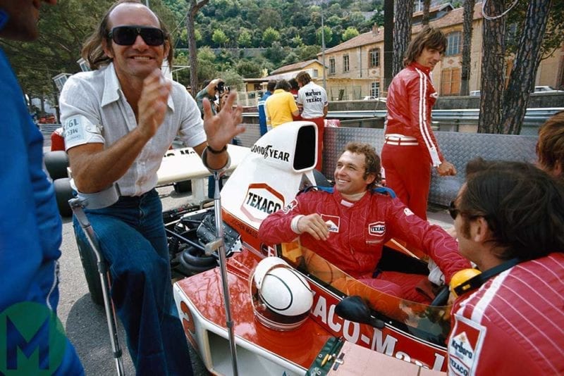 Mike Hailwood laughing with Jochen Mass in his McLaren at 1975 Monaco GP