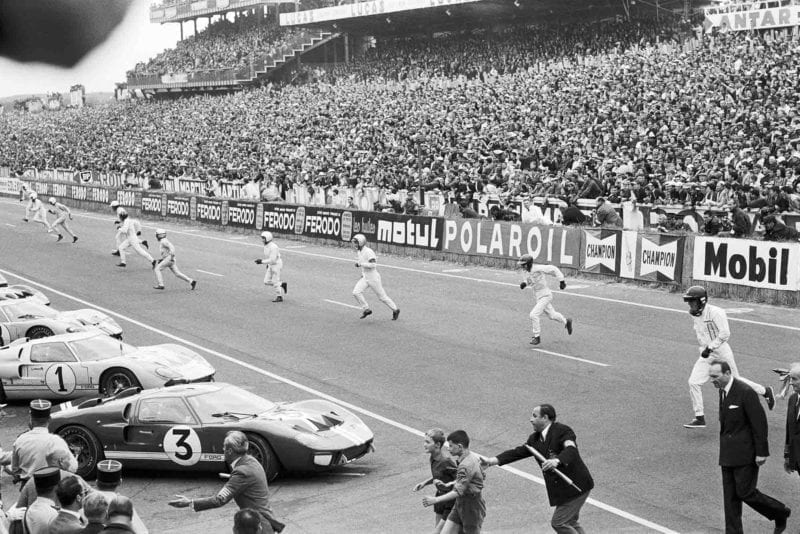 Drivers run to their cars at the start of 1966 Le Mans, with Dan Gurney on the right heading to his Ford GT40 MkII, followed by Ken Miles, John Whitmore, Bruce McLaren, Pedro Rodriguez, Graham Hill, Mike Parkes and Jean Guichet.