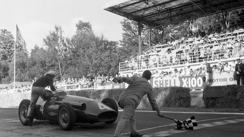 Oil splattered Jean Behra climbs out of his MAserati at the finish line of 1957 French GP
