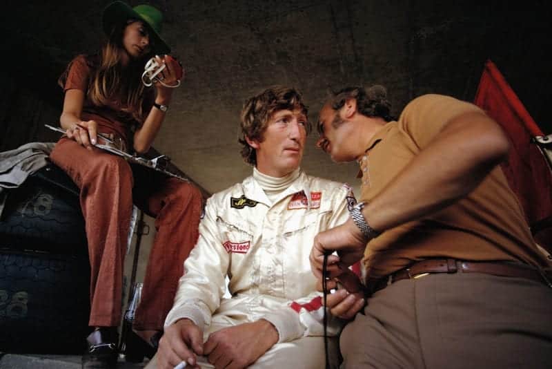 Jochen Rindt confers with Lotus team boss COlin Chapman whilst sitting next to wife Nina at the 1970 Austrian Grand Prix.