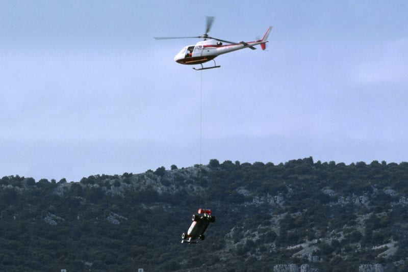 The Alfa Romeo 179C of Mario Andretti is lifted off the circuit by helicopter.