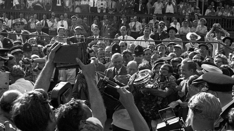 Stirling Moss surrounded by crowds after winning the 1955 British Grand Prix at Aintree