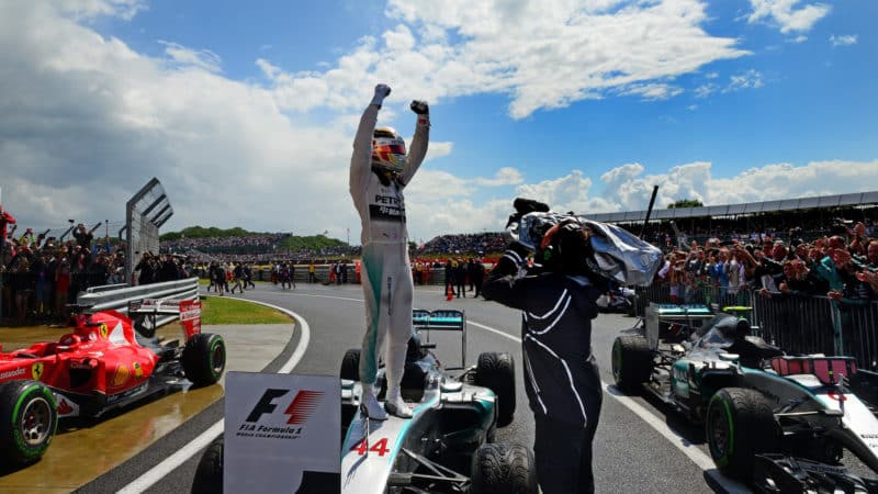 Lewis Hamilton stands in victory pose on his Mercedes after winning the 2015 British Grand Prix