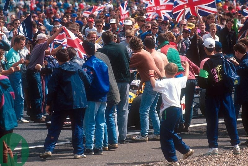 The Silverstone crowd surrounds Nigel Mansell's car on track at the 1992 British Grand Prix