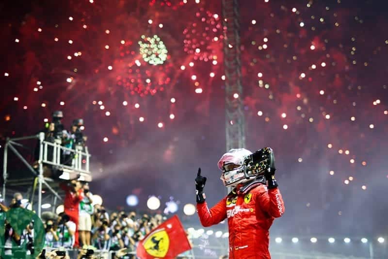 Sebastian Vettel holds his steering wheel in the air beneath fireworks after winning the 2019 Singapore Grand Prix