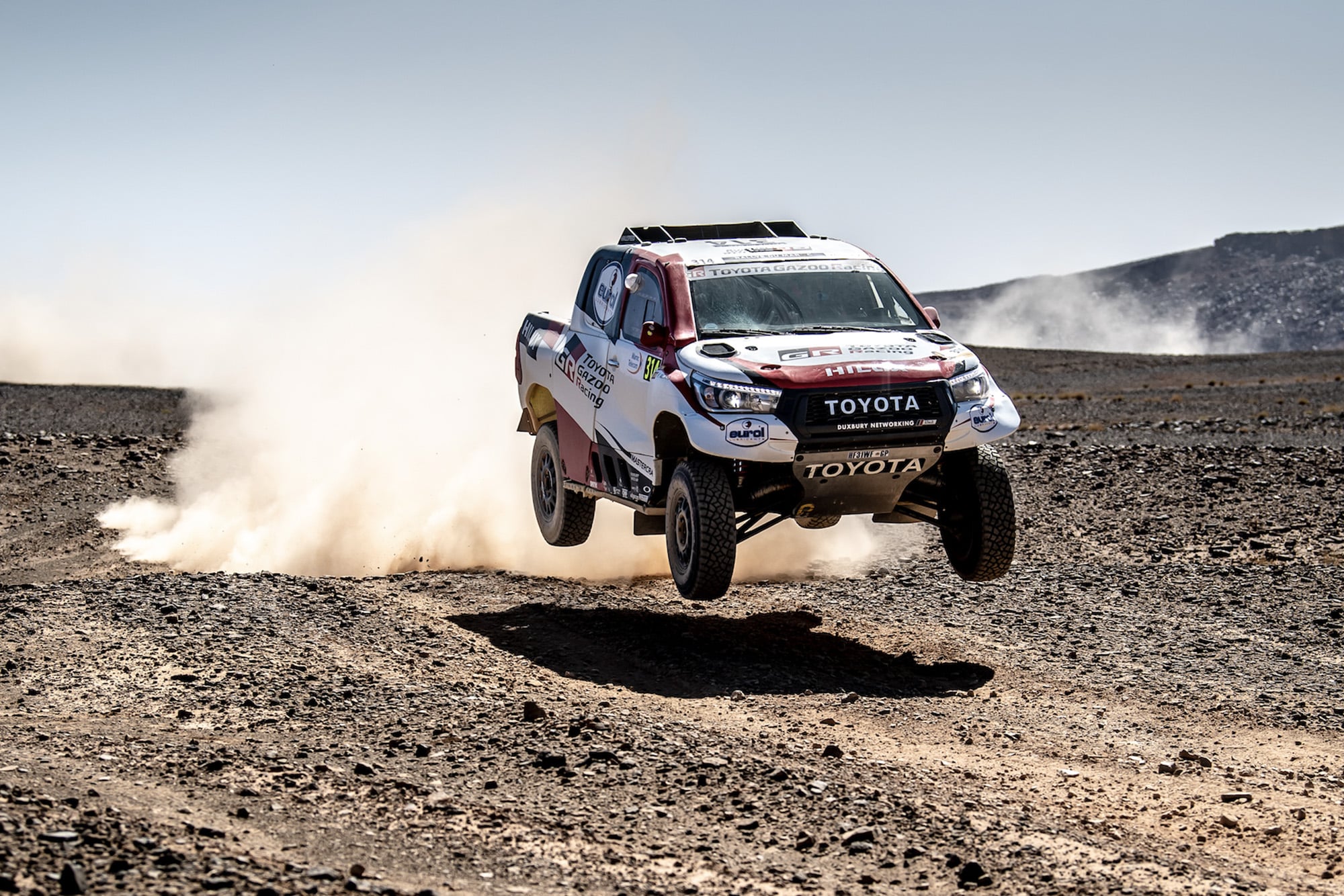 Fernando Alonso's Dakar-spec Toyota Hilix jumping over a rally raid course