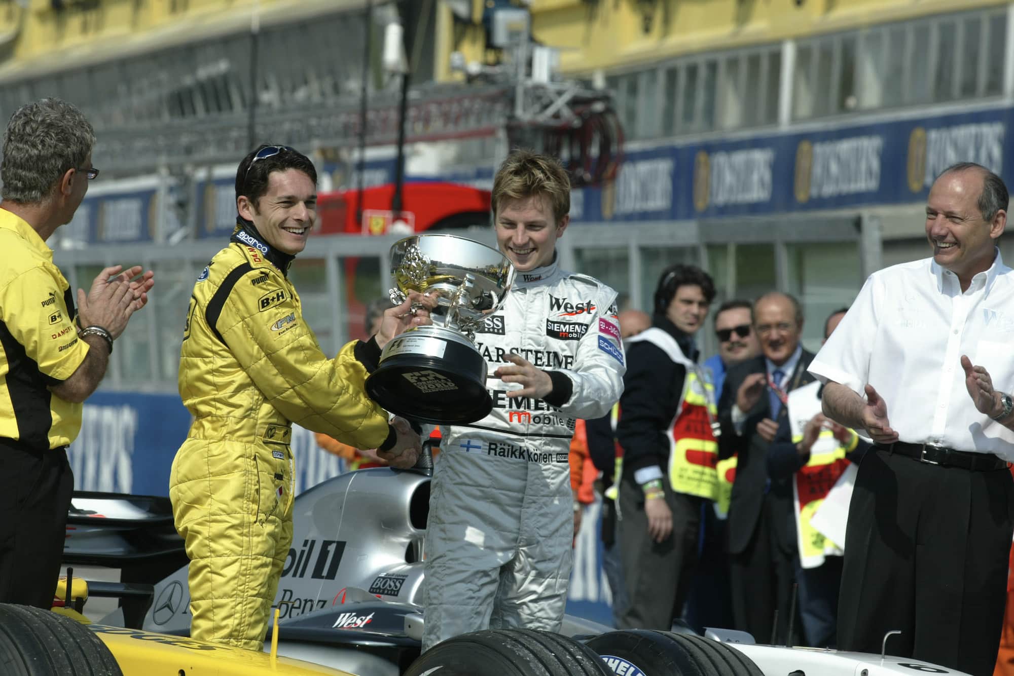 Kimi Raikkonen hands the winning trophy for the 2003 F1 Brazilian Grand Prix to Giancarlo Fisichella