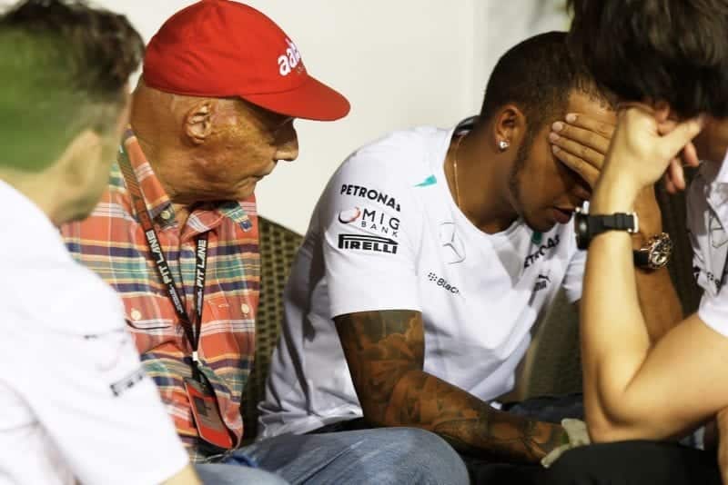 Niki Lauda sits next to Lewis Hamilton who has his head in his hands