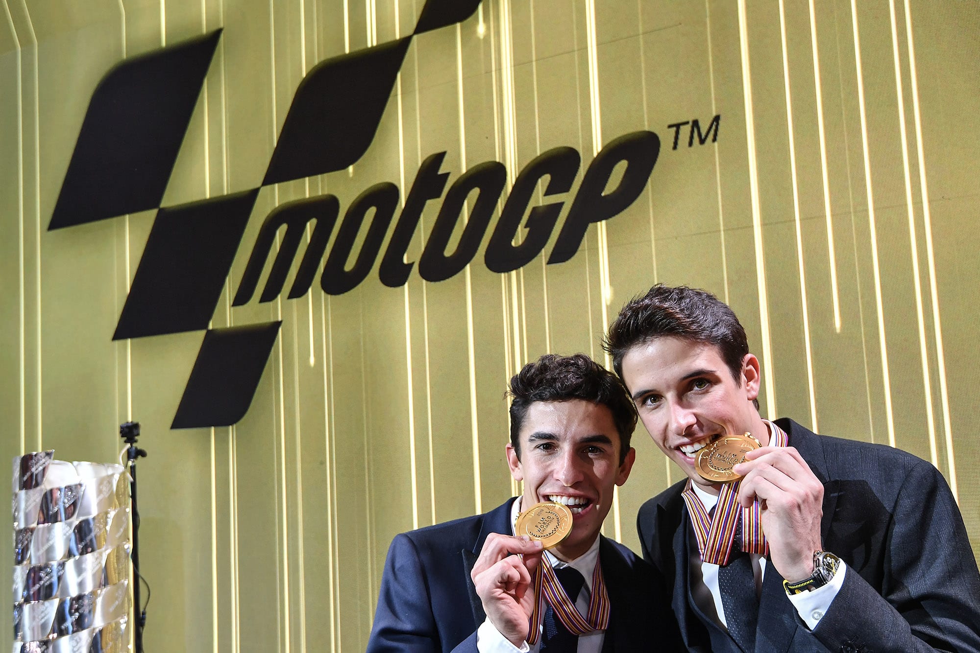 Marc Marquez and Alex Marquez bite their MotoGP and Moto2 championship medals for the camewras