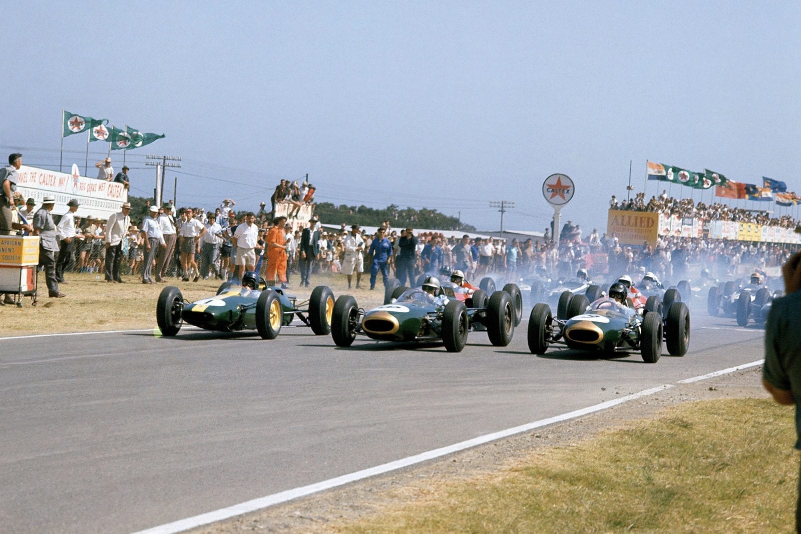 Jim Clark (Lotus 25-Climax), Jack Brabham (Brabham BT7-Climax) and Dan Gurney (Brabham BT7-Climax) lead off the front row of the grid at the start.
