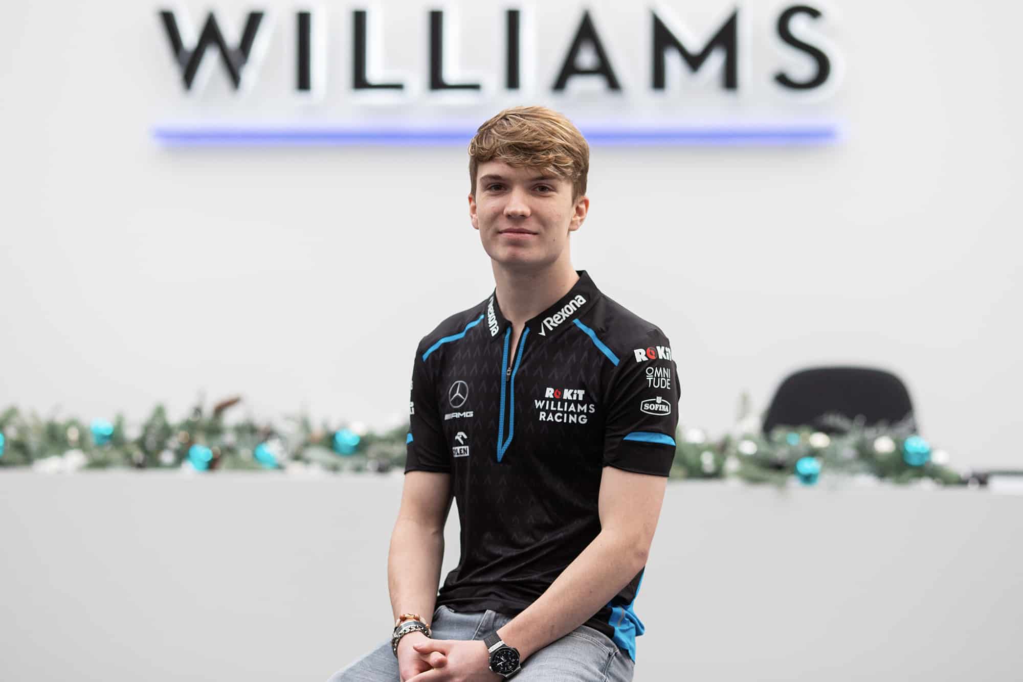 Dan Ticktum in front of a Williams sign as he announces his 2020 role as development driver