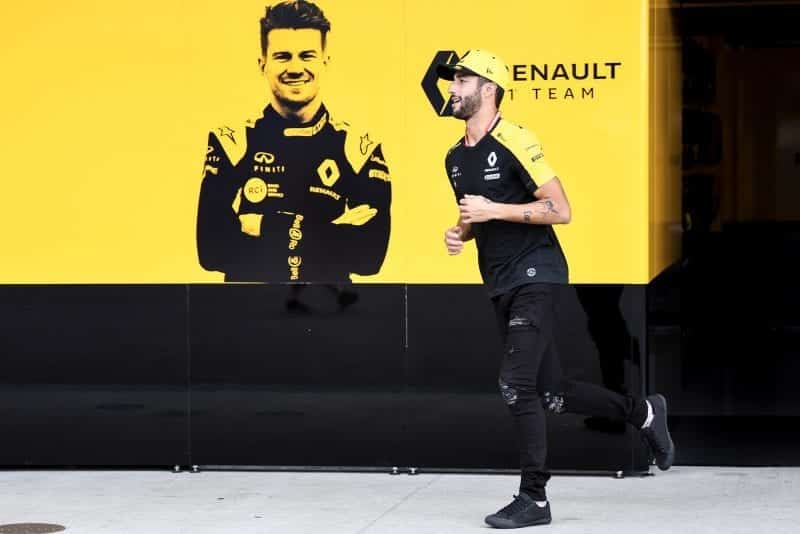 Daniel Ricciardo runs past a board showing his Renault team-mate Nico Hulkenberg
