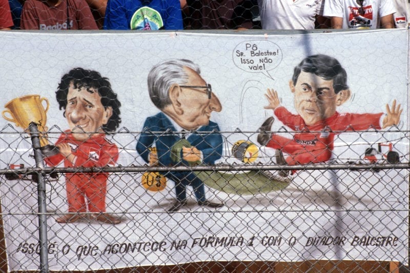 Fans at the 1990 Brazilian Grand Prix hang a banner showing Jean Marie Balestre pulling the rug from under Ayrton Senna