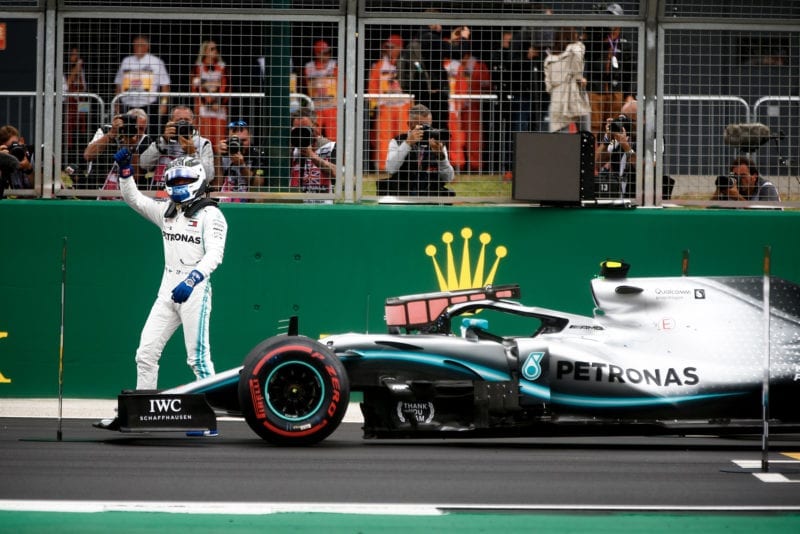Valtteri Bottas celebrates next to his Mercedes W10 after taking pole position at the 2019 British GP