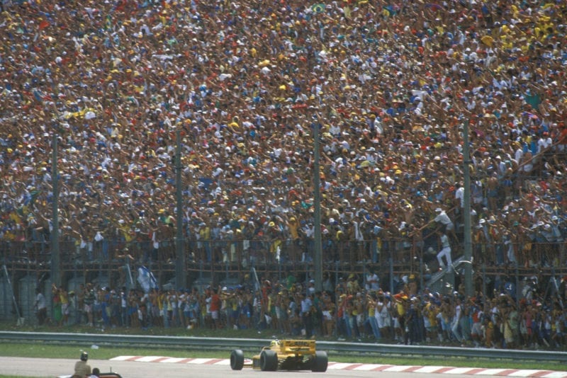 Ayrton Senna drives in front of a packed grandstand of fans at the 1987 Brazilian Grand Prix