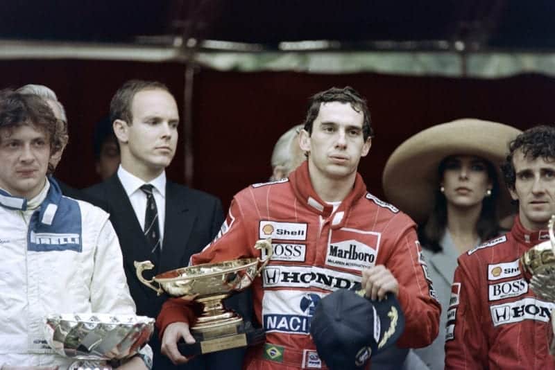 An exhausted Ayrton Senna clutches his trophy after winning the 1989 Monaco Grand Prix