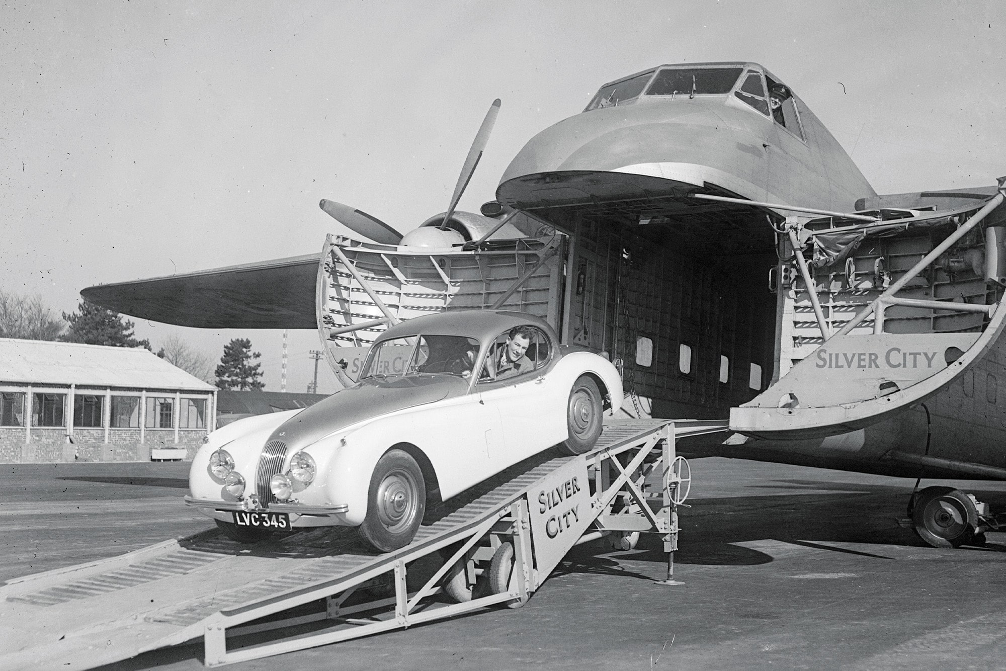 Stirling Moss drives a Jaguar XK120 out of the nose of a cargo plane