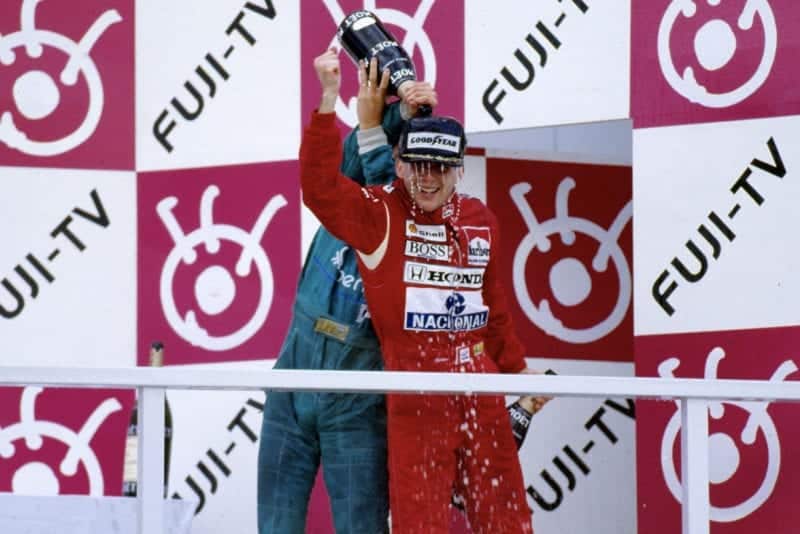 Thierry Boutsen pours champagne over Ayrton Senna on the podium at the 1988 Japanese Grand Prix