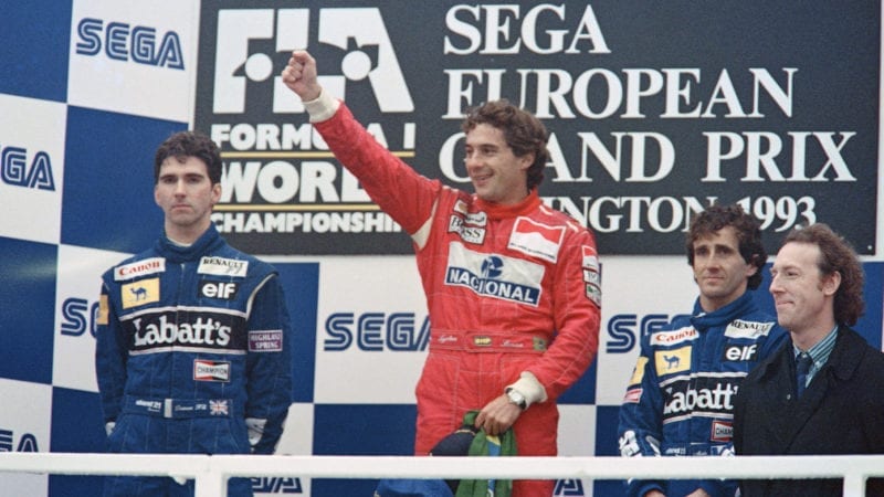 Ayrton Senna raises his arm in triumph next to Damon Hill and Alain Prost on the podium after winning the 1993 F1 European Grand Prix at Donington Park