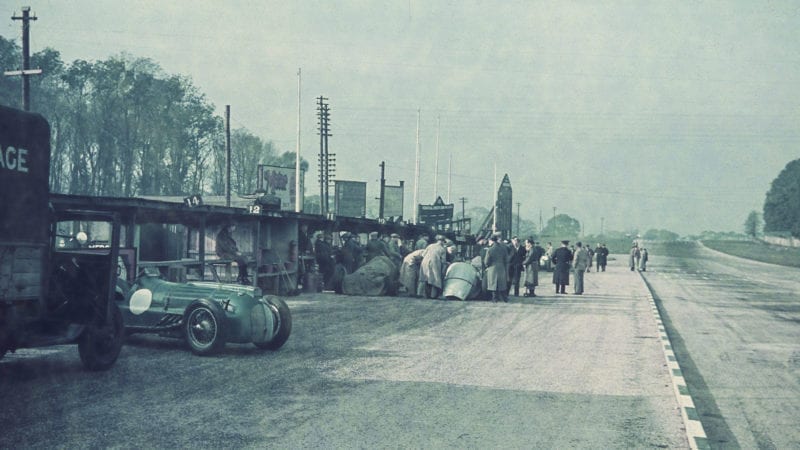 The pitlane ahead of the 1938 Donington Grand Prix with an Ecurie Bleue Delahaye and covered Mercedes W154s