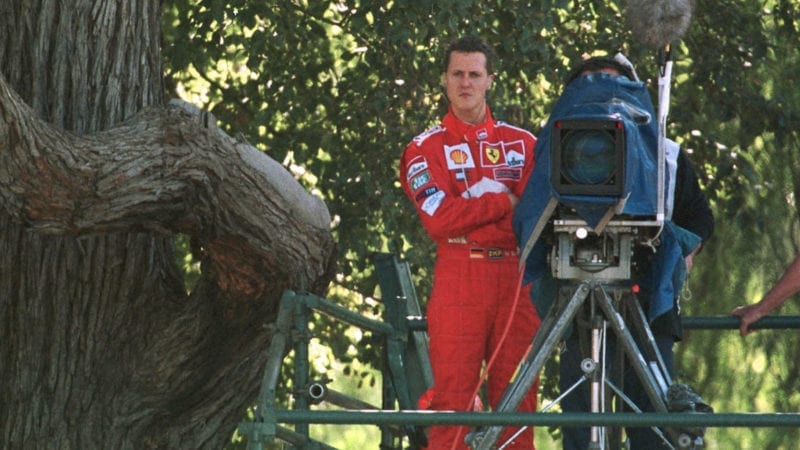Michael Schumacher stands next to a TV camera