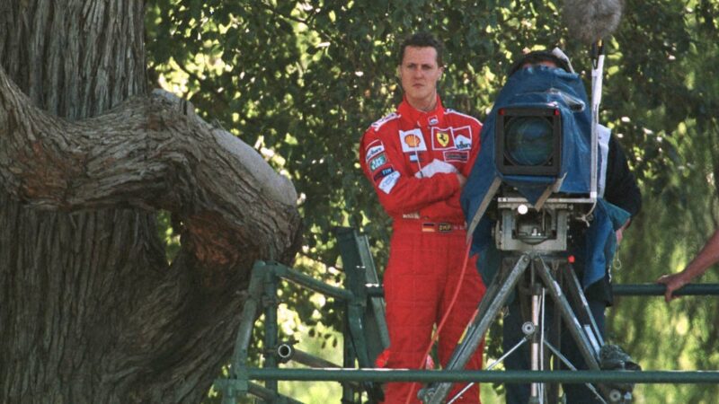 Michael Schumacher stands next to a TV camera