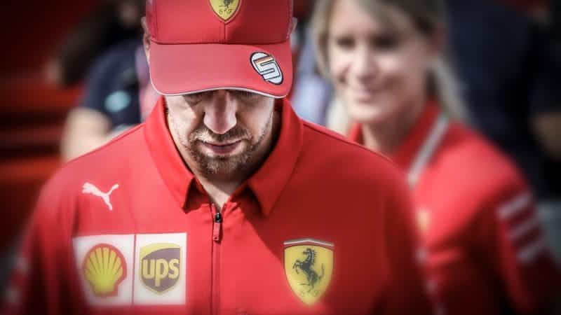 Sebastian Vettel in Ferrari clothing with his head down and cap on