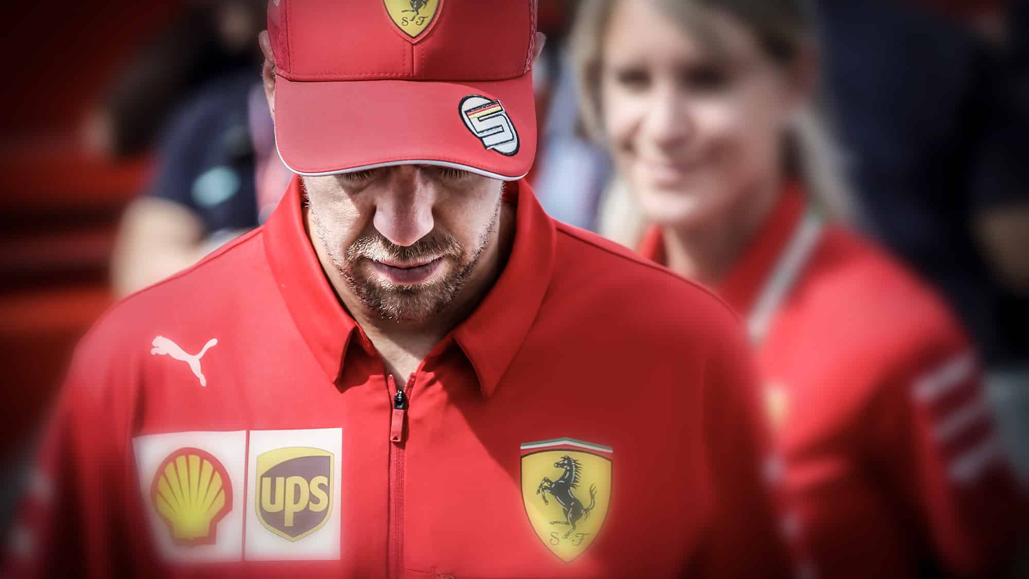 Sebastian Vettel in Ferrari clothing with his head down and cap on