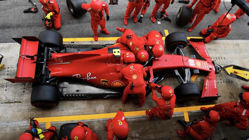 Mechanics fasten Charles Leclerc's seatbelts in the pits at the 2020 f1 Spanish Grand Prix
