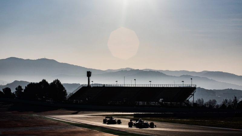 Mountains in the background of the Circuit de Catalunya as two F1 cars drive past during 2020 preseason testing