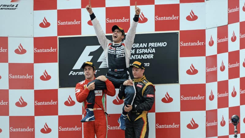 Pastor Maldonado is held up by Fernando Alonso and Kimi Raikkonen on the podium after winning the 2012 F1 Spanish Grand Prix