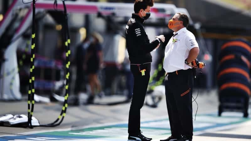 Toto Wolff and Zak Brown talk to each other in an F1 pitlane