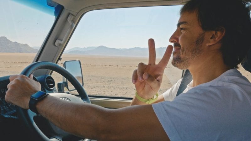 Fernando Alonso gives a V for victory sign as he drives in the desert
