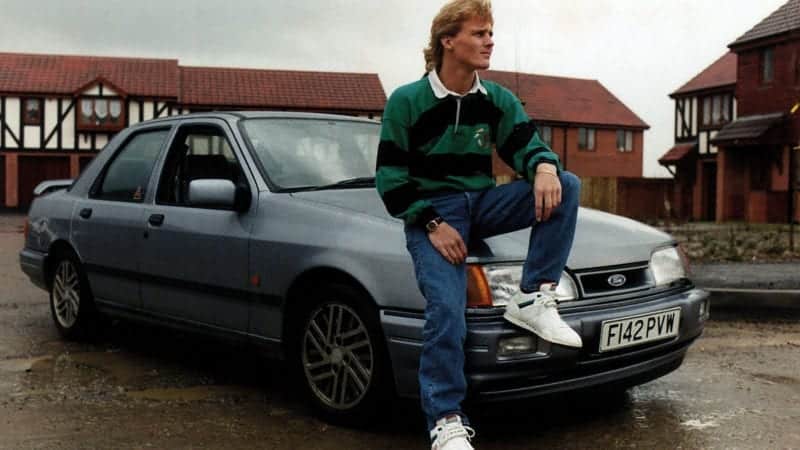 Johnny Herbert sits on the bonnet of a Ford Sierra