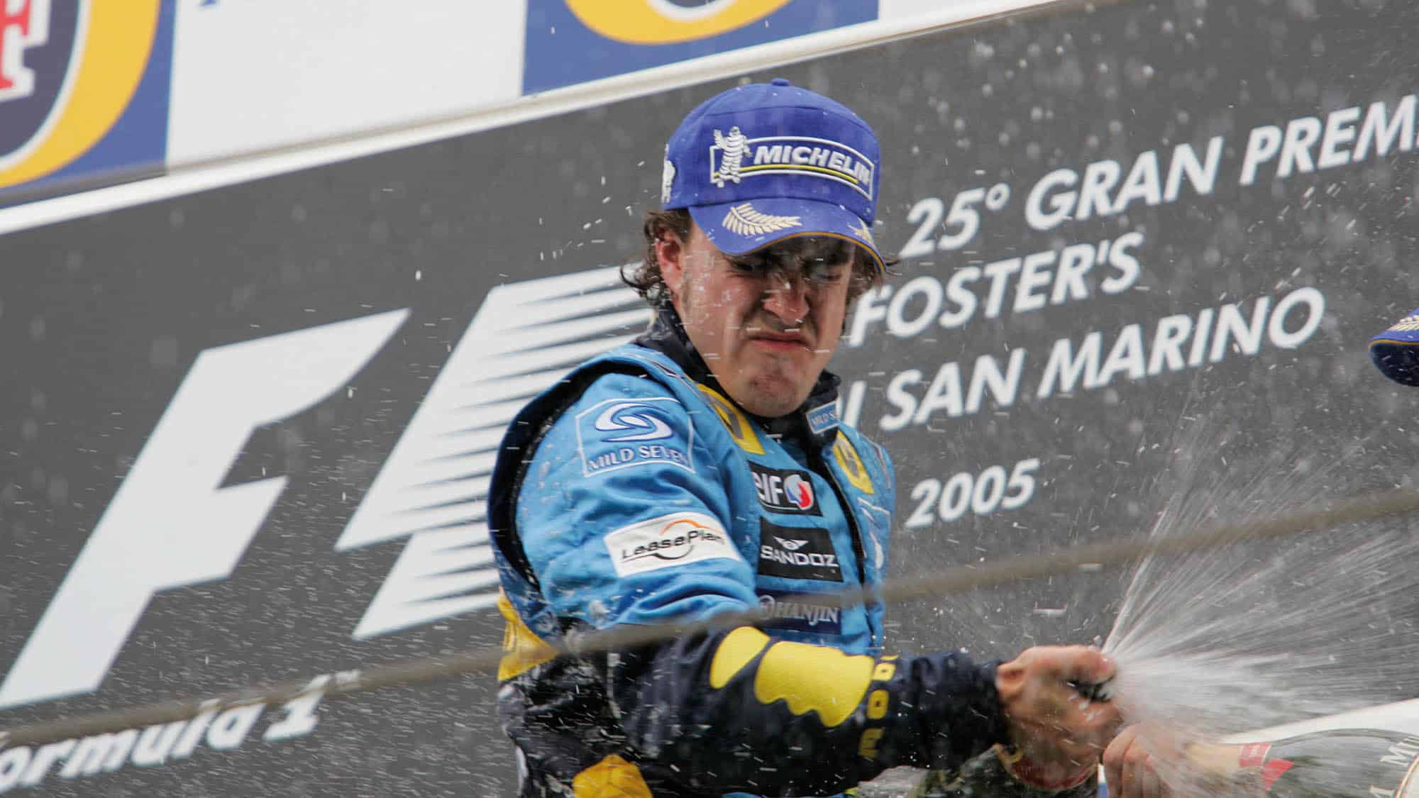 FErnando Alonso celebrates winning the 2005 San MArino Grand Prix with champagne on the podium at Imola