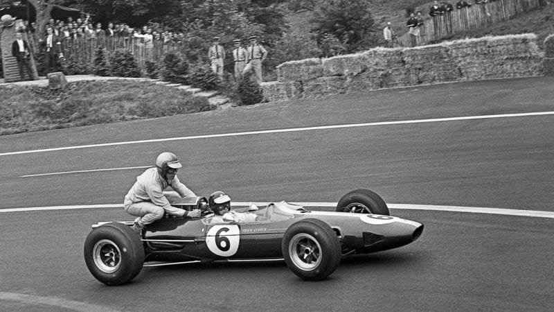 Jim Clark gives Mike Spence a lift to the pits on the back of his Lotus 25 at the 1965 French Grand Prix