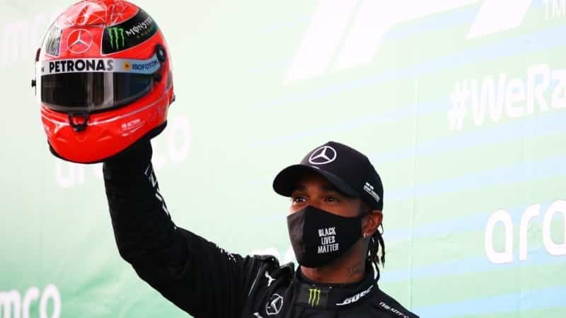 Lewis Hamilton holds a Michael Schumachr helmet in the air after equaling his record F1 wins at the Nurburgring in the 2020 Eifel Grand Prix
