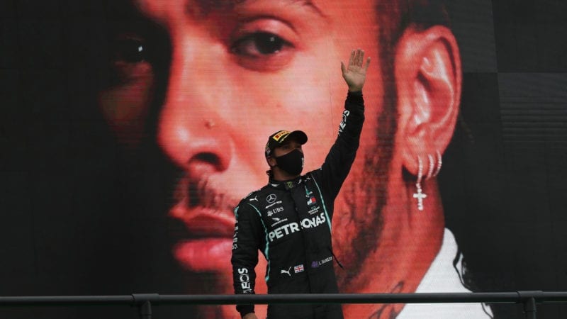 Lewis Hamilton raises his arms in front of a giant picture of himself after winning a record 92nd F1 race at the 2020 Portuguese Grand prix