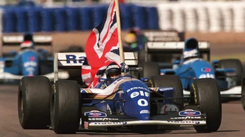 Damon Hill holds a Union flag in his Williams after winning the 1994 British Grand Prix at Silverstone