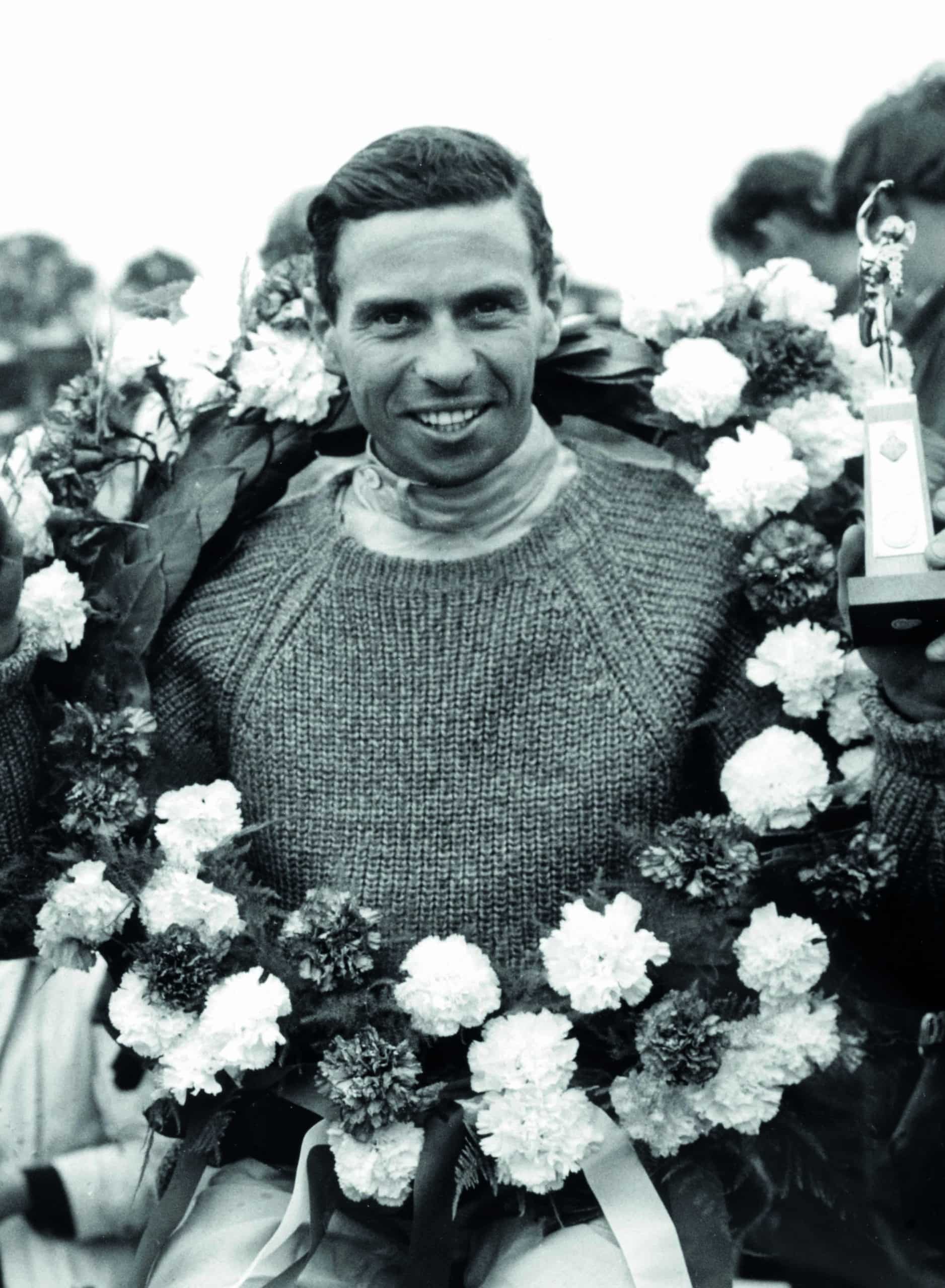 Jim-Clark-celebrates-winning-the-1965-British-Grand-Prix-at-Silverstone-with-a-garland-around-his-neck