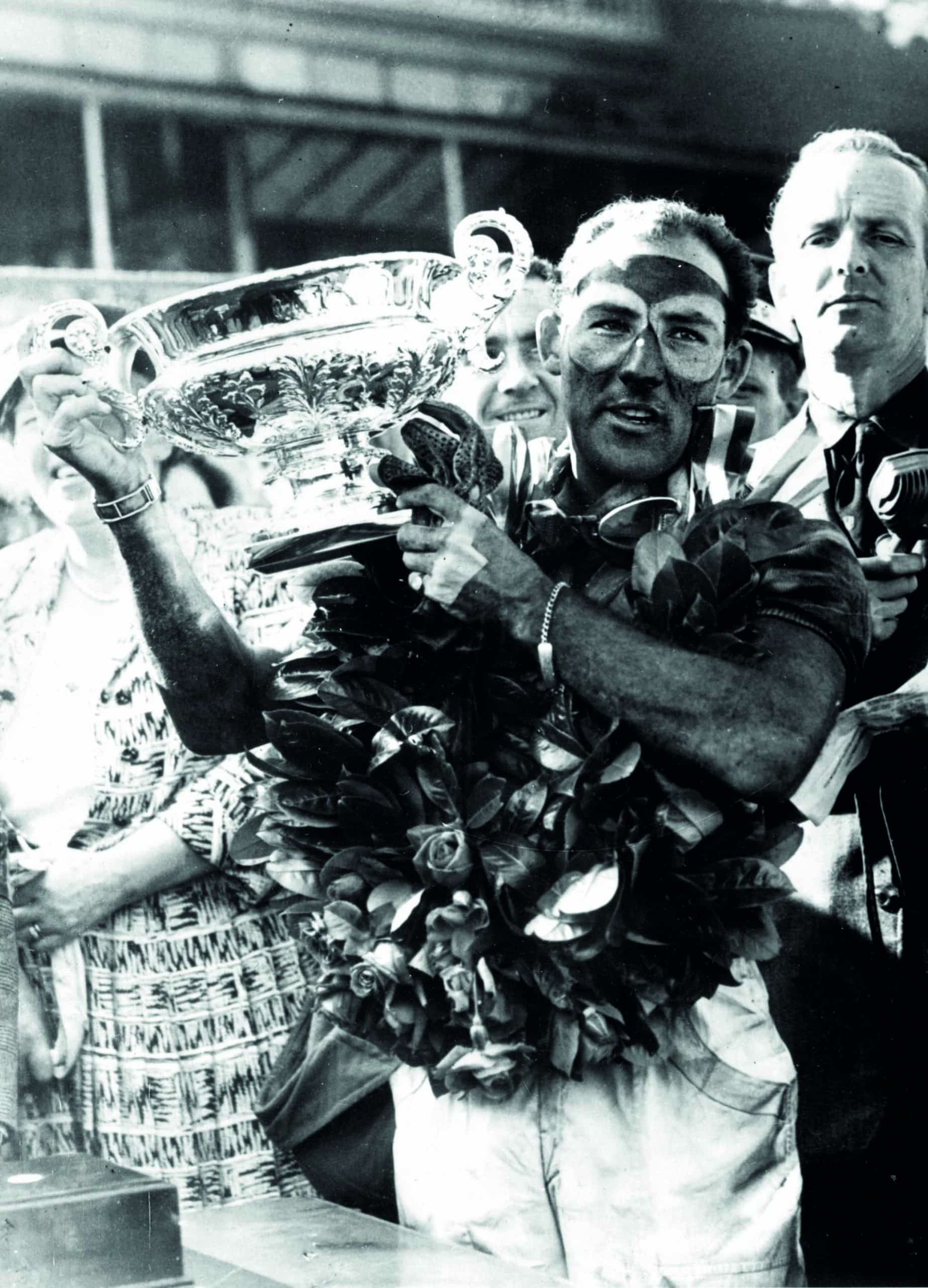 Stirling-Moss-raises-the-winning-trophy-from-the-1955-British-Grand-Prix-at-Aintree