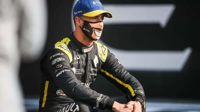 Daniel Ricciardo wears a face mask showing a big smile