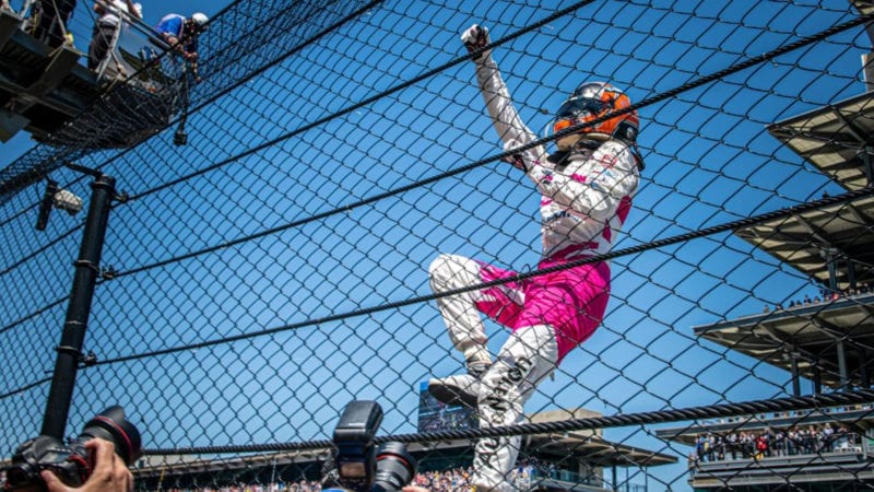 Helio Castroneves climbs the fence after winning the 2021 Indy 500