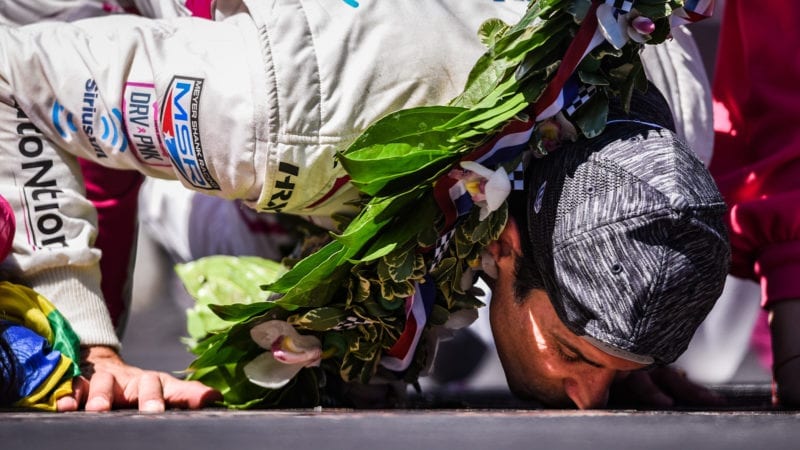 Helio Castroneves kisses the bricks after winning the 2021 Indy 500