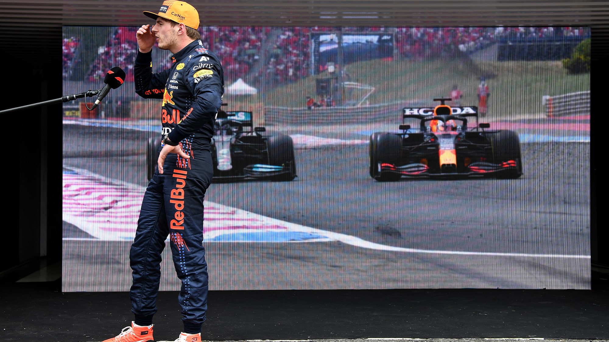 Max Verstappen in front of video of him overtaking Lewis Hamilton at the 2021 French Grand Prix