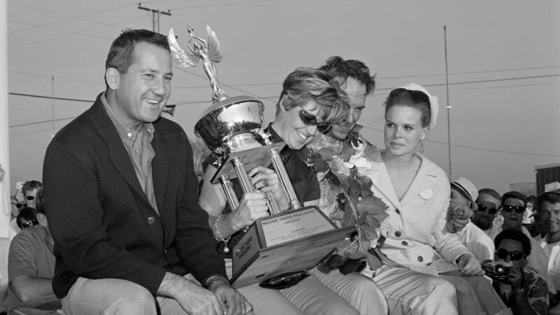 UNITED STATES - JANUARY 22: 1968 Motor Trend 500 - Riverside - NASCAR. Race winner Dan Gurney celebrates his victory with Race queen far right and Petersen Publishing founder Robert E. Petersen (left). (Photo by Eric Rickman/The Enthusiast Network via Getty Images/Getty Images)