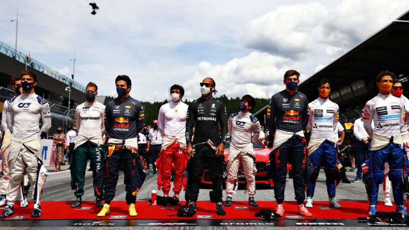 SPIELBERG, AUSTRIA - JUNE 27: Pierre Gasly of France and Scuderia AlphaTauri, Sebastian Vettel of Germany and Aston Martin F1 Team, Sergio Perez of Mexico and Red Bull Racing, Carlos Sainz of Spain and Ferrari, Yuki Tsunoda of Japan and Scuderia AlphaTauri, Lewis Hamilton of Great Britain and Mercedes GP, Max Verstappen of Netherlands and Red Bull Racing, Daniel Ricciardo of Australia and McLaren F1 and Lando Norris of Great Britain and McLaren F1 stand for the national anthem on the grid ahead of the F1 Grand Prix of Styria at Red Bull Ring on June 27, 2021 in Spielberg, Austria. (Photo by Dan Istitene - Formula 1/Formula 1 via Getty Images)