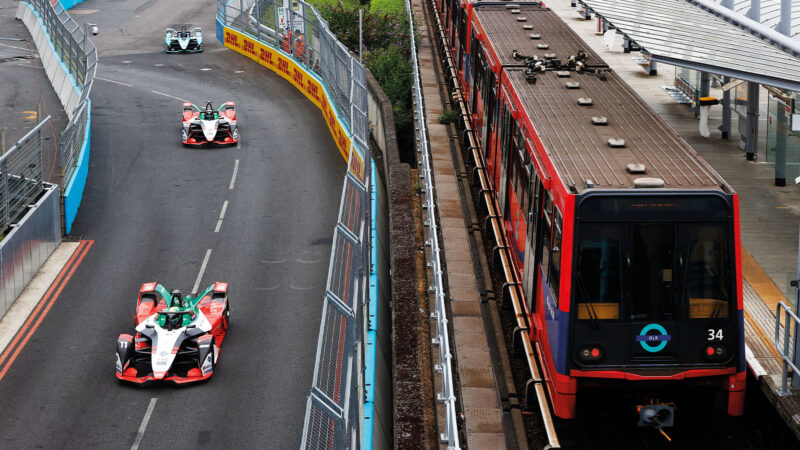 Formula E cars race alongside a DLR train at the 2021 London e-Prix