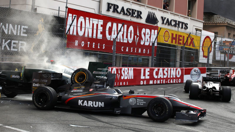 Drivers passe by the crashed car of Lotus racing's Italian driver Jarno Trulli (L) and HRT F1's Indian driver Karun Chandhok at the Monaco street circuit on May 16, 2010, during the Monaco Formula One Grand Prix. AFP PHOTO / GUILLAUME BAPTISTE (Photo credit should read GUILLAUME BAPTISTE/AFP via Getty Images)