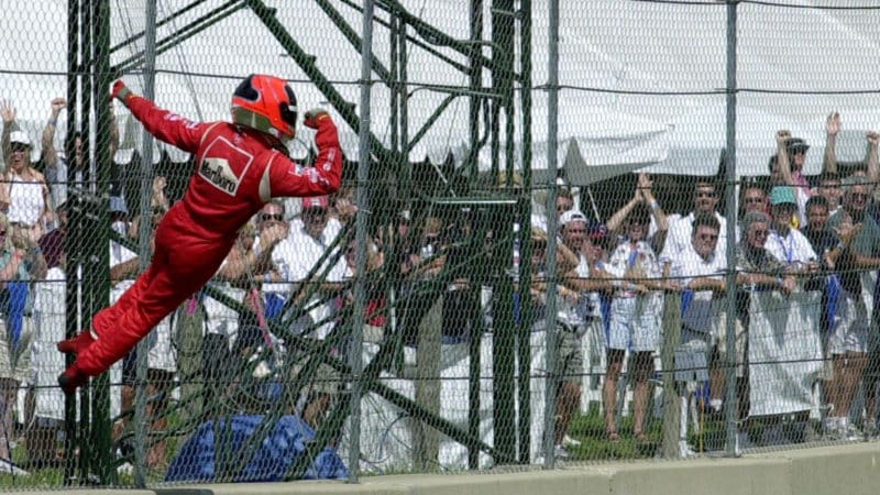 Spider Man Helio Castroneves climbs the fence at Ohio IndyCar race in 2000